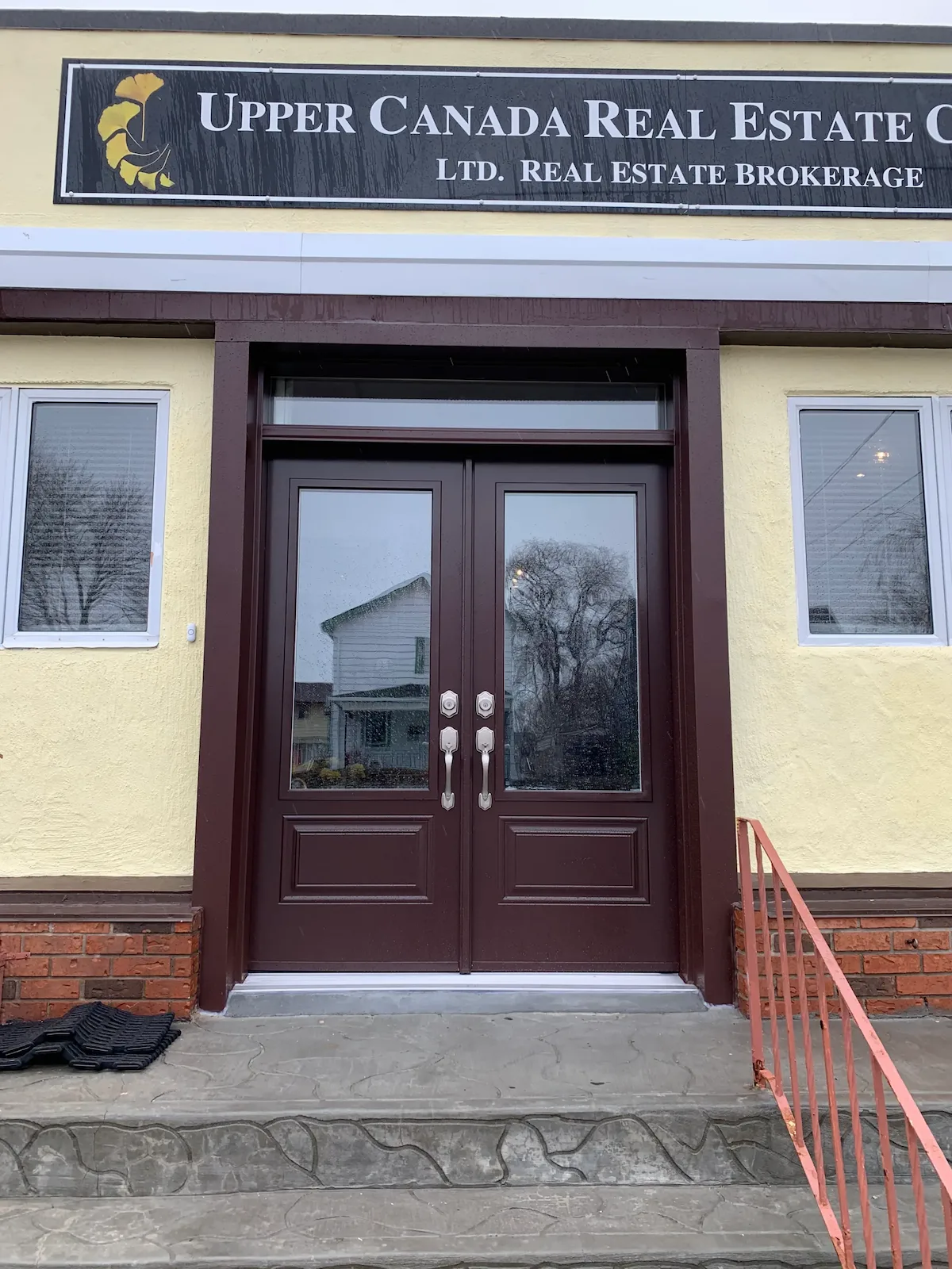 Brown double entry doors with a transom installed by Great Northern Home Exteriors