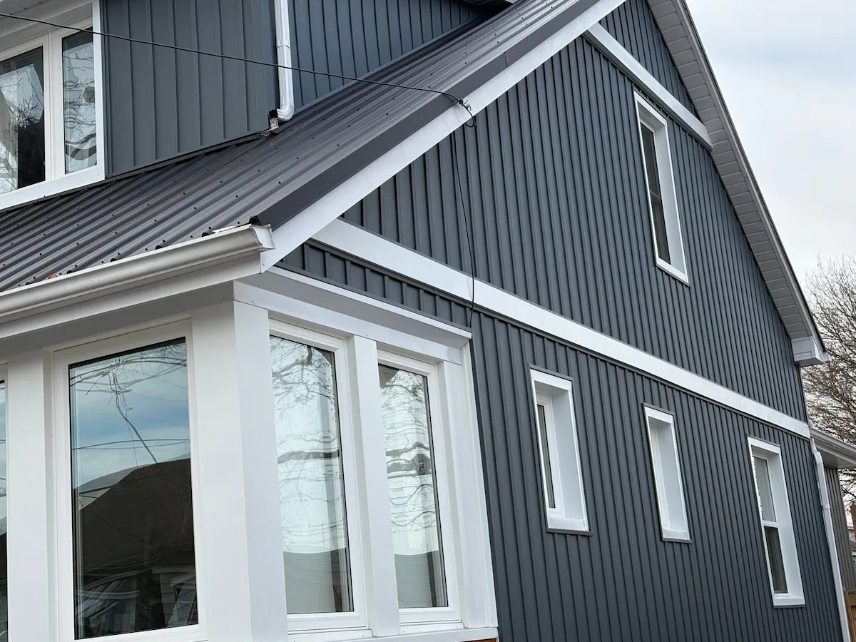 Dark board-and-batten siding with white window and exterior trim