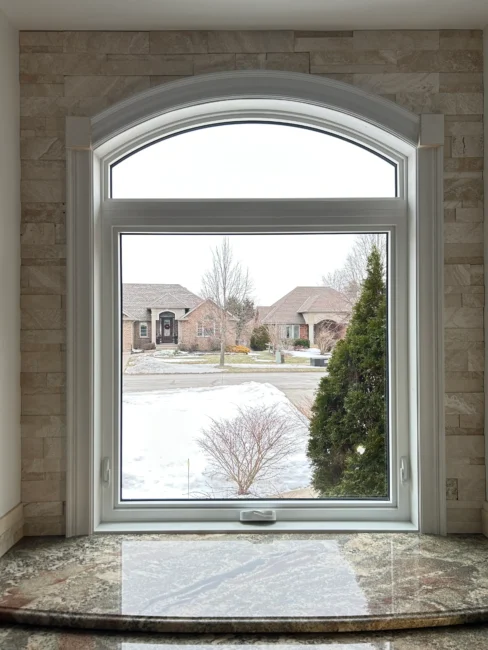 Custom arched awning window installed in a kitchen with detailed interior trim.