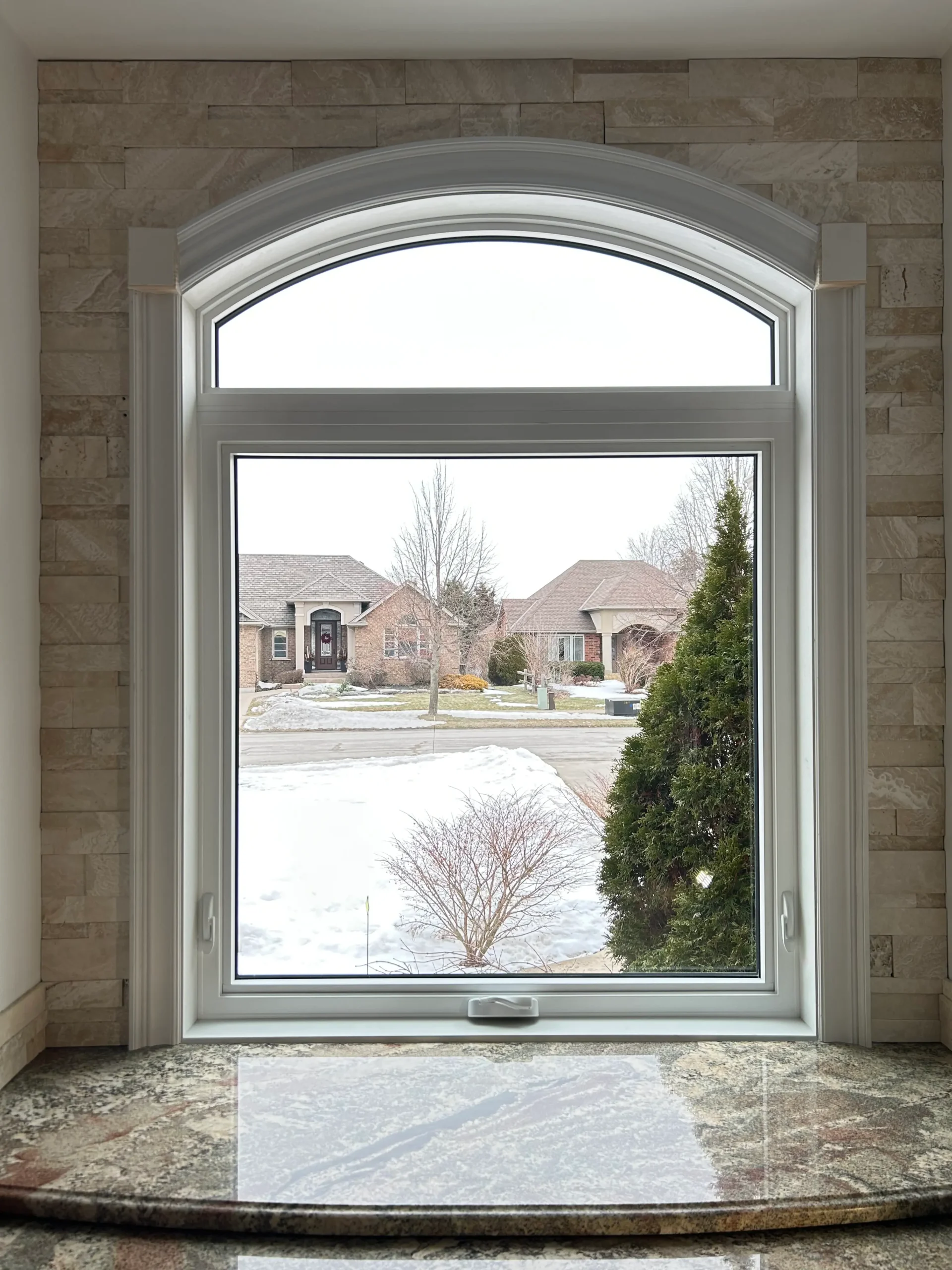 Custom arched awning window installed in a kitchen by Great Northern Home Exteriors