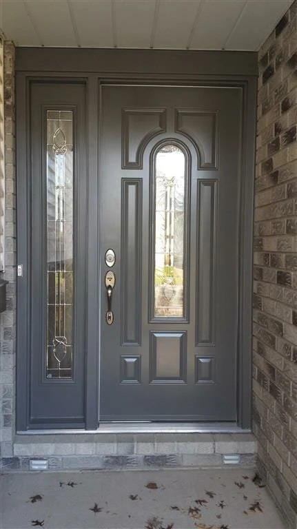 Grey Steel Entry Door with Sidelight Installed in Welland Grey steel entry door with decorative glass sidelight installed on a brick home in Welland